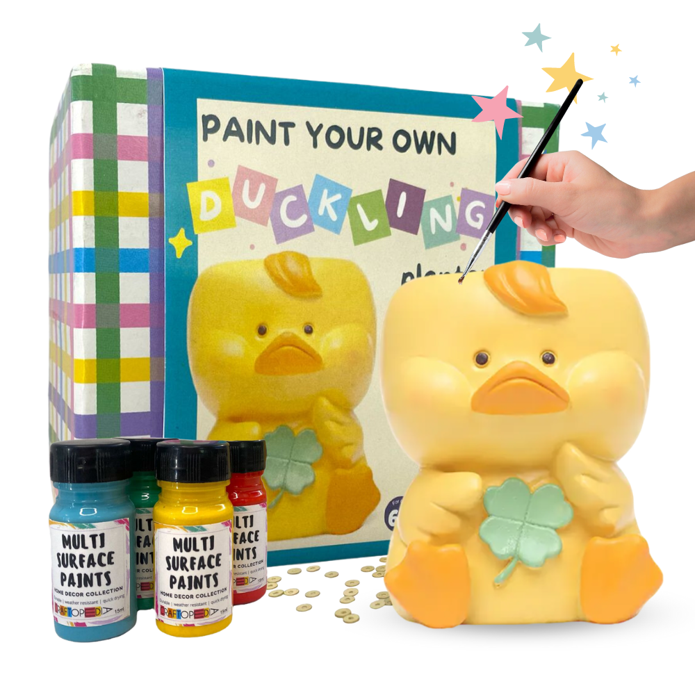 A 'Paint Your Own Pen Stand' kit with a duckling design, including a yellow duckling sculpture, a set of multi-purpose surface paints, and paintbrushes.