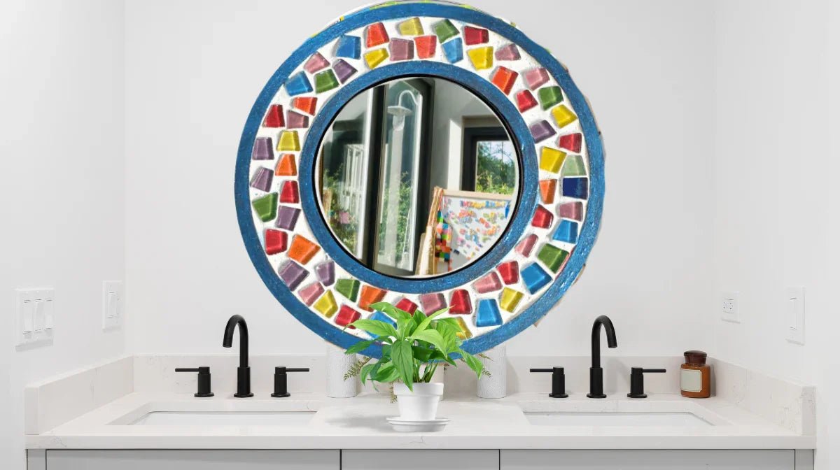 Modern bathroom double sink with black faucets, white countertop, colorful round mosaic mirror, and green potted plant